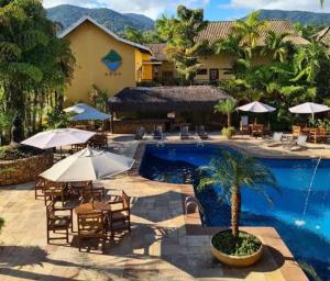 a resort with a swimming pool with tables and umbrellas at Ilha Flat Hotel Suíte Bella - 4207 - Ilhabela in Ilhabela