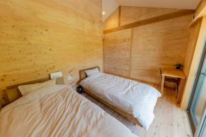 a bedroom with two beds in a wooden room at Guest House Amami Long Beach 2 - Vacation STAY 36312v in Amami