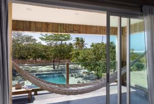 a hammock on the balcony of a house with a pool at Casa Uca in Guriú