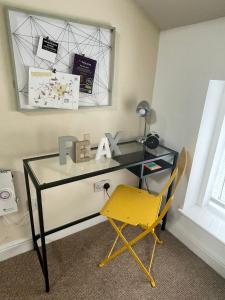 a desk with a yellow chair and a mirror at Flat 2 Chestergate in Macclesfield