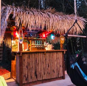 un bar con techo de paja y hamaca en Airstream Woodland Escape, en Galston