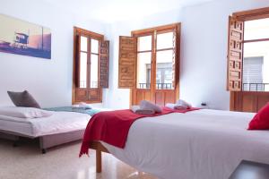 a bedroom with two beds and two windows at 1D Apartamento con vistas a la Alhambra in Granada