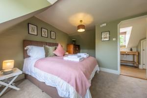 a bedroom with a large bed with a pink blanket at Heavenly 16th century cottage in pretty rural village - Swan's Nest in Boxford