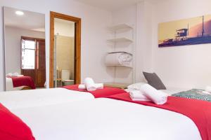 a bedroom with two beds with red and white sheets at 1D Apartamento con vistas a la Alhambra in Granada