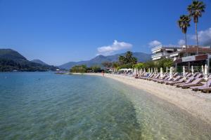 a beach with chaise lounges and chairs on it at Edward Art Boutique Hotel in Nydri