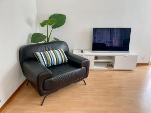 a black leather chair in a living room with a television at alscher's holiday home in Interlaken