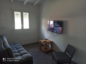 een woonkamer met een bank en een tv aan de muur bij Saint Rose : Charmant T3 proche de la plage in Plessis-Nogent