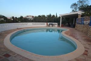 a swimming pool with blue water in a brick patio at Casa do Milho in Carvoeiro