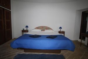 a bedroom with a large bed with blue sheets at Casa do Milho in Carvoeiro