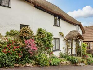 a thatched cottage with flowers in front of it at Rose Cottage in Holcombe in Dawlish