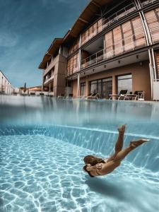 a woman laying in the water in a swimming pool at Hôtel & Spa Villa Seren in Hossegor