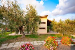 a house with a tree and flowers in a yard at Agriturismo L'Istrice di Giò in Montalto di Castro