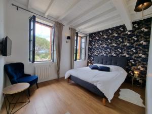 a bedroom with a bed and a blue chair at Les Granges de Jules in Lafitte-Vigordanne +37 photos