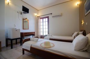 a hotel room with two beds and a television at Almira Inn in Ios Chora