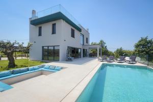 une villa avec une piscine en face d'une maison dans l'établissement Villa Grisi, à Vižinada