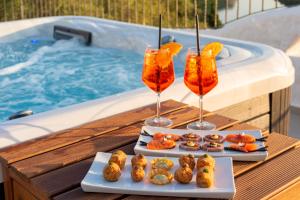 a table with two drinks and appetizers next to a swimming pool at Hotel Villa Cedrino in Dorgali