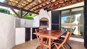 an outdoor kitchen with a wooden table and chairs at Villa Palmeira Galé Beach in Albufeira