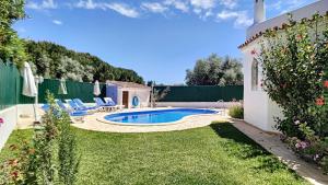 a backyard with a pool and chairs and a fence at Villa Palmeira Galé Beach in Albufeira