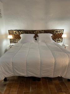 a large bed with white sheets and pillows at Le Petit Egregore, patio et climatisation in Lauris