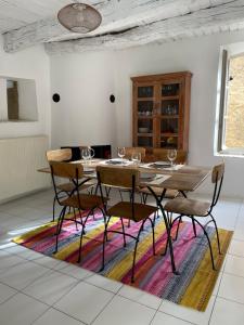 a dining room with a table and chairs on a rug at Le Petit Egregore, patio et climatisation in Lauris