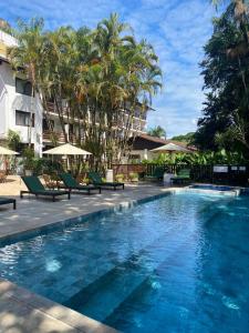 una piscina en un hotel con sillas y palmeras en Timbó Park Hotel, en Timbó