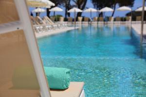 a pool with chairs and umbrellas and a towel at Iberostar Selection Santa Eulalia Adults-Only Ibiza in Santa Eularia des Riu