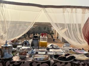 a table with plates of food and a drink on it at Candy Camp in Merzouga