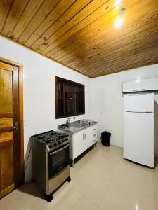 eine Küche mit einem Herd, einer Spüle und einem Kühlschrank in der Unterkunft Cantinho do Nono 2 in Campos do Jordão