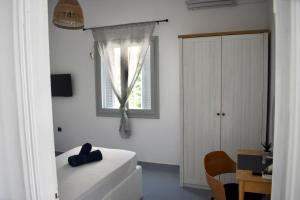 a white bedroom with a bed and a window at The Greek side of life! in Artemida