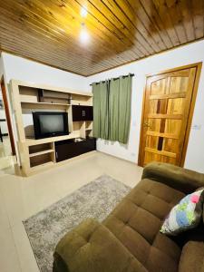 ein Wohnzimmer mit einem Sofa und einem Flachbild-TV in der Unterkunft Cantinho do Nono 2 in Campos do Jordão