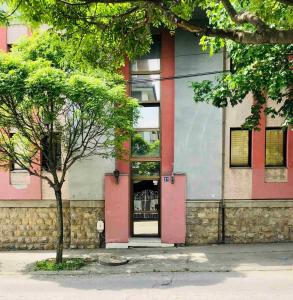 a building with a pink door and a tree at KRAGUJ apartments 1 in Kragujevac