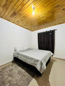 ein Schlafzimmer mit einem Bett und einer Holzdecke in der Unterkunft Cantinho do Nono 2 in Campos do Jordão