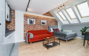 a living room with a red couch and a brick wall at Saint Florian's Suites - Old Town Luxury Apartments - by Upstairs in Kraków
