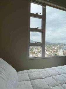 - une chambre avec un lit blanc et une fenêtre dans l'établissement 1BR Unit - MIGAs Haven @ One Pavilion Place, à Cebu