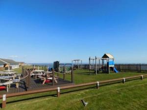 een park met een speeltuin met tafels en een glijbaan bij Fernly Holiday Home in Corton