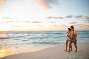 a couple walking on the beach at sunset at Le Blanc Spa Resort Cancun Adults Only All-Inclusive in Cancún