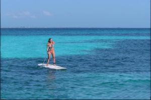 a woman standing on a surfboard in the ocean at Le Blanc Spa Resort Cancun Adults Only All-Inclusive in Cancún
