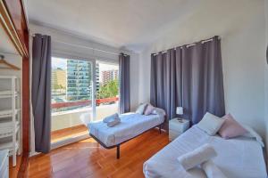 a bedroom with two beds and a large window at Nura Houses Duplex Magaluf 5 in Magaluf