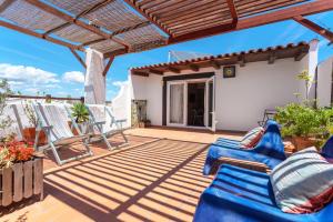 a patio with blue chairs and a pergola at Downtown Alegria B&B in Tavira