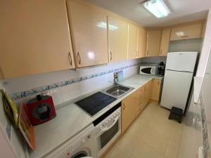 una pequeña cocina con fregadero y nevera. en Apartamentos Punta Canaret Altamar, en Alcossebre