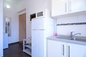 a white kitchen with a sink and a refrigerator at Villa Fio - Rooms & Studio in Hvar