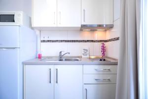 a white kitchen with a sink and a refrigerator at Villa Fio - Rooms & Studio in Hvar
