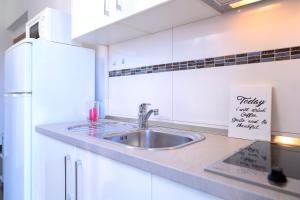 a white kitchen with a sink and a refrigerator at Rooms & Studio Villa Fio in Hvar