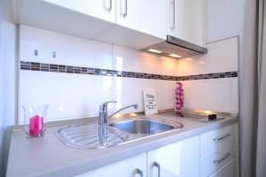 a kitchen with a sink and white cabinets at Villa Fio - Rooms & Studio in Hvar