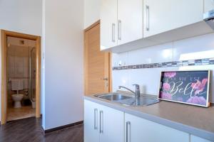 a kitchen with white cabinets and a sink at Villa Fio - Rooms & Studio in Hvar