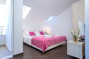 a white bedroom with a bed with a pink blanket at Villa Fio - Rooms & Studio in Hvar