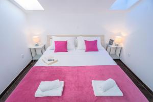 a bedroom with a large white bed with pink pillows at Villa Fio - Rooms & Studio in Hvar