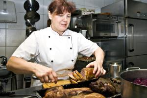 Eine Frau in einer Küche, die Essen auf einer Theke zubereitet. in der Unterkunft Gasthof zum Hirsch in Görisried