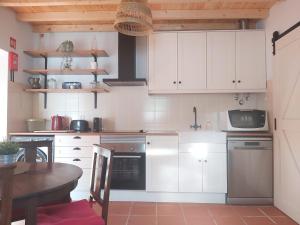 une cuisine avec des placards blancs et une table avec une table dans l'établissement QUINTA DAS TEIMOSAS by Stay in Alentejo, à Cercal