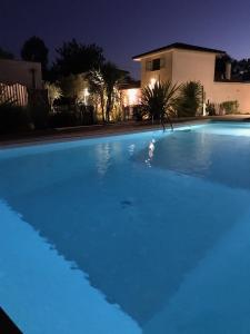 ein nachts beleuchteter Pool in der Unterkunft Le Clos Fleuri proche de Bordeaux in Saint-Sulpice-et-Cameyrac